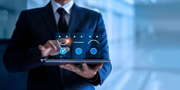 Businessman touching and drawing face emoticon smile on the tablet, service mind. blue background. Customer service concept.